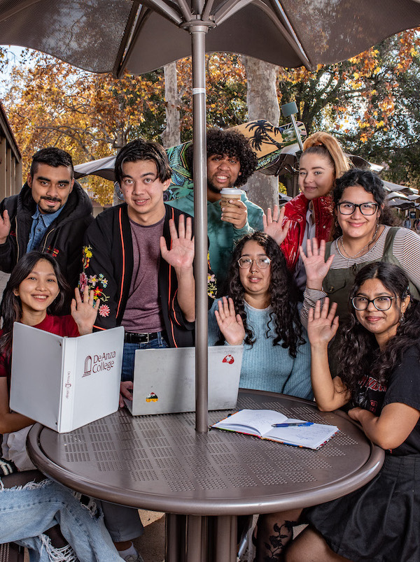 students sitting around table and waving