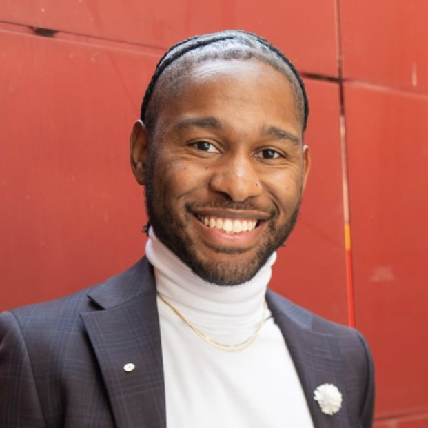 Tim Herd. Man smiling in front of red background